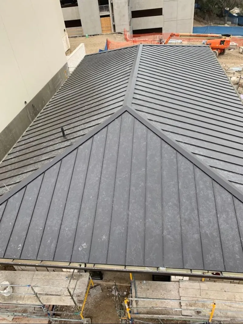 Commercial metal roof construction with crane equipment in Orosi